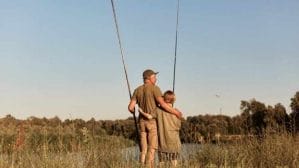 father with his son outdoors fishing by lake holding fishing rods bin hands standing near lake having rest wearing casual clothing wants catching fish cropped 19